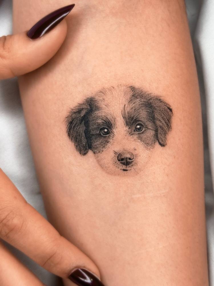 Micro-realistic style dog portrait tattoo located on the inner forearm.