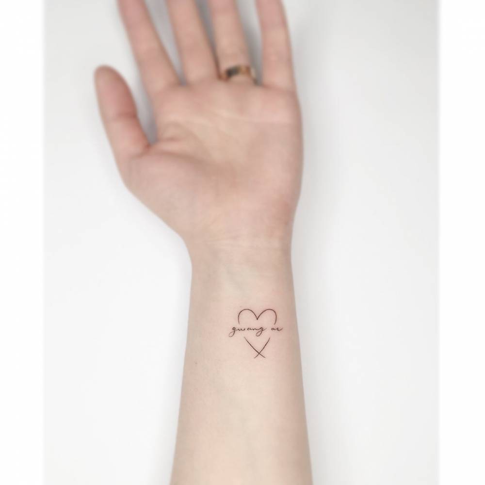 Heart and banner tattoo in minimalistic style located on the wrist.