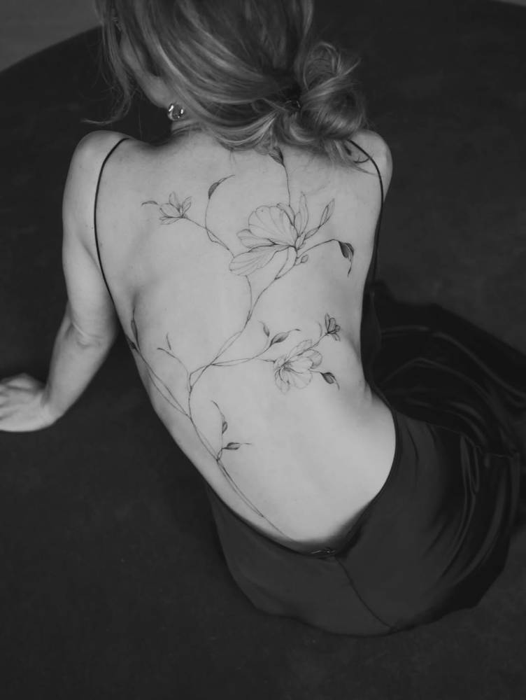 Floral back composition tattoo in illustrative style.