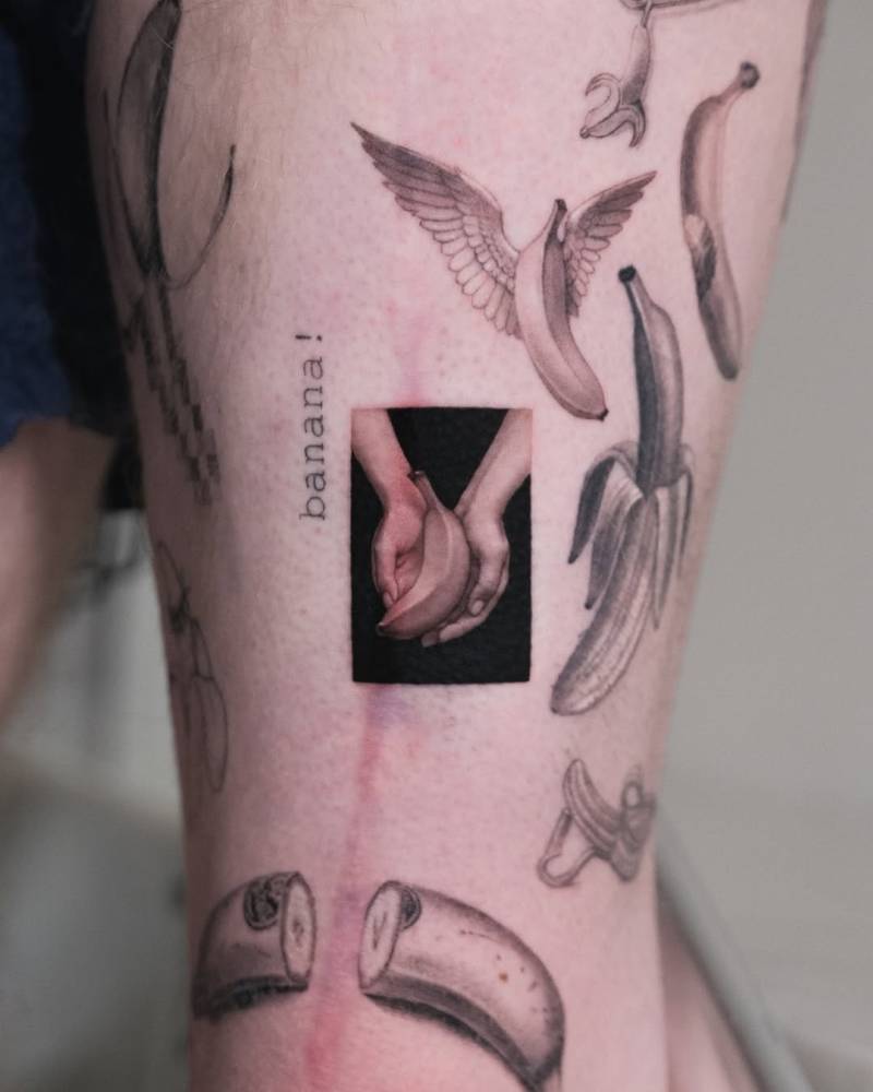 Hands holding a banana tattooed on the thigh, micro-realistic style.