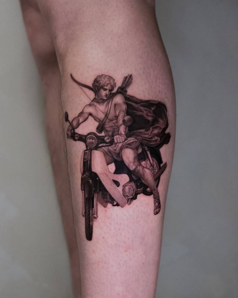Micro-realistic style Cupid riding a motorbike tattoo located on the shin.