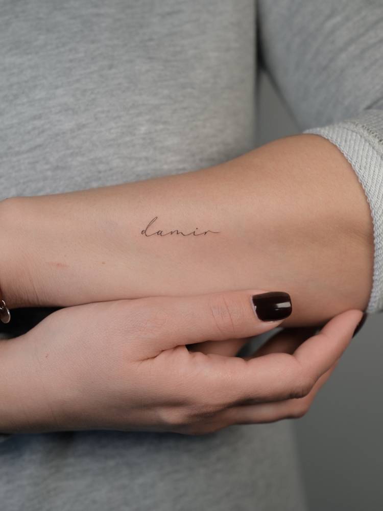 Lettering tattoo of the name "Damir" located on the forearm.