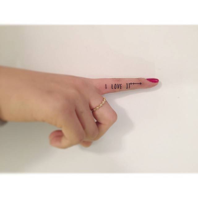 "I love it" lettering tattoo located on the finger.