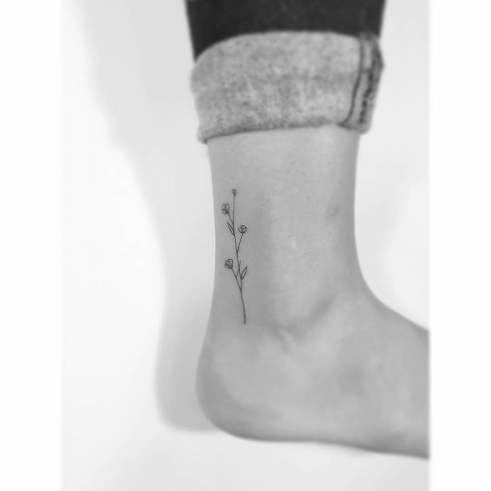 Fine line style flowers tattoo located on the ankle.