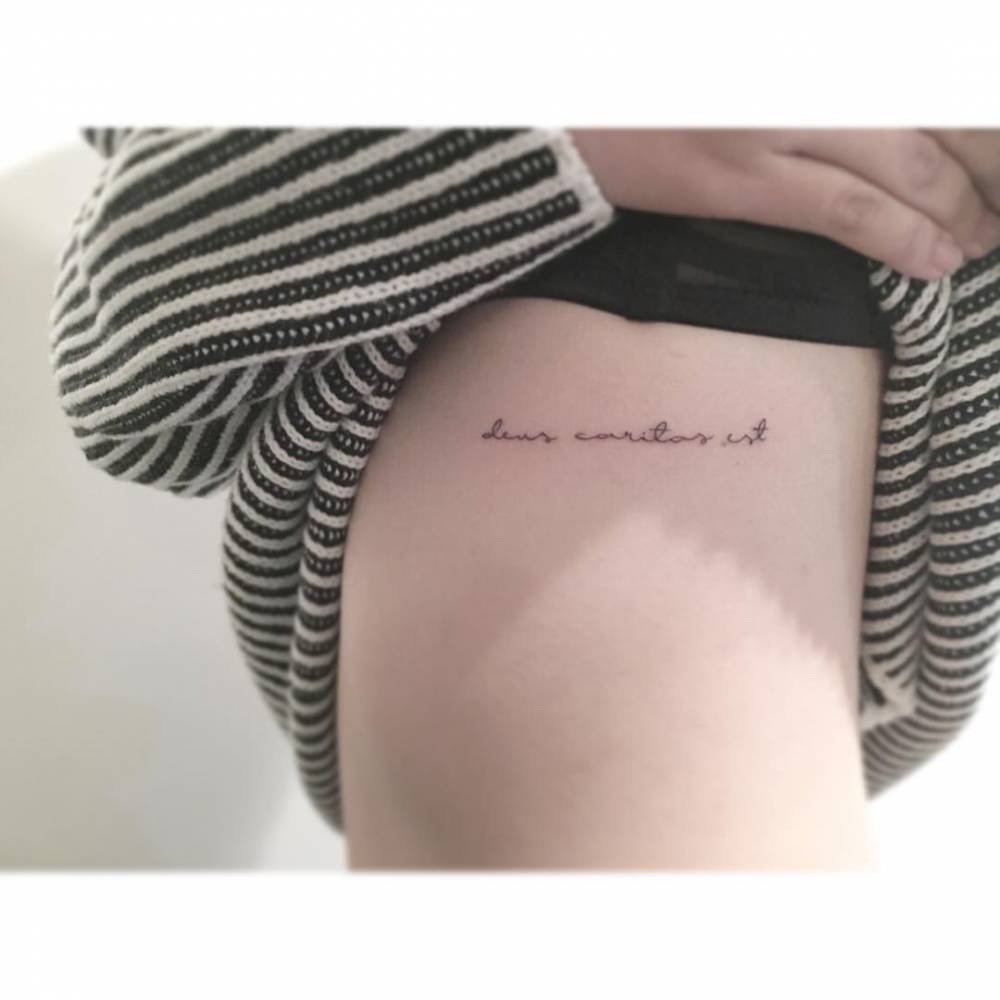 "Deus caritas est" lettering tattoo located on the rib.