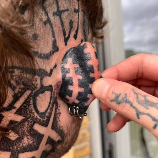 Negative space blackwork style tattoo located behind the ear.