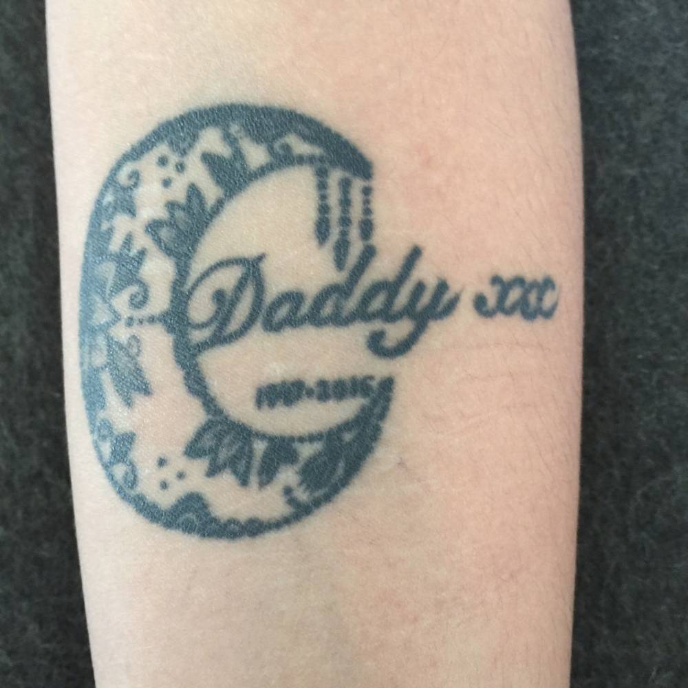 Ornamental moon and word "daddy" tattooed on Alexandria Zahra Jones's inner forearm, in memory of her father, David Bowie.