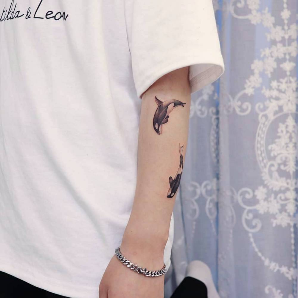 Orcas tattoo located on the forearm, micro-realistic style.