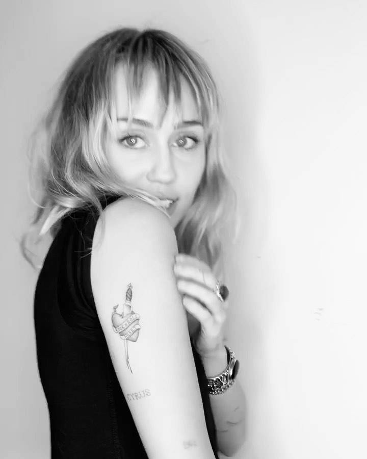 Heart and dagger with banner tattooed on  MIley Cyrus' tricep.