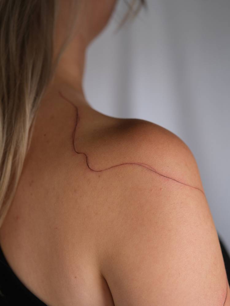 Free hand abstract line tattooed on the shoulder.