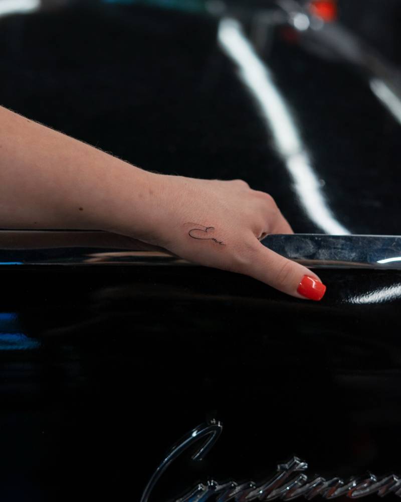 Script font name “Emi” tattooed on the hand.