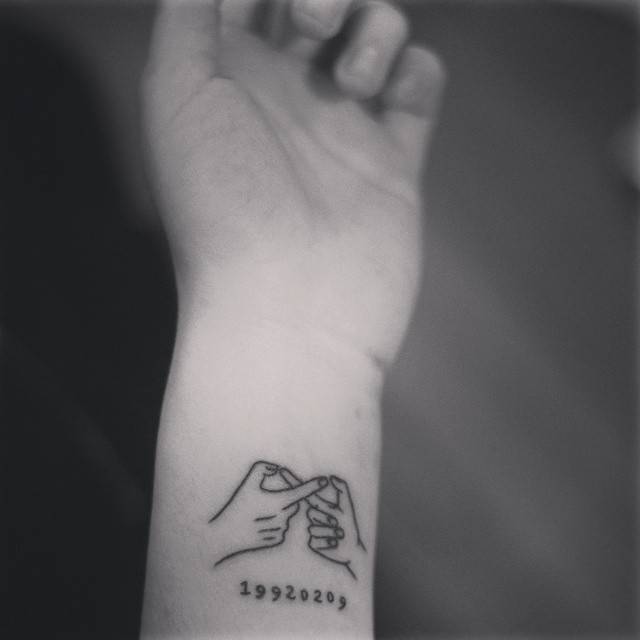 Hands making infinity symbol tattooed on the wrist.