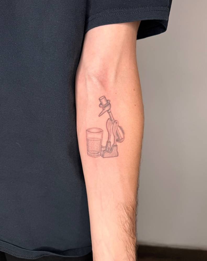 Drinking bird tattoo located on the inner forearm, illustrative style.