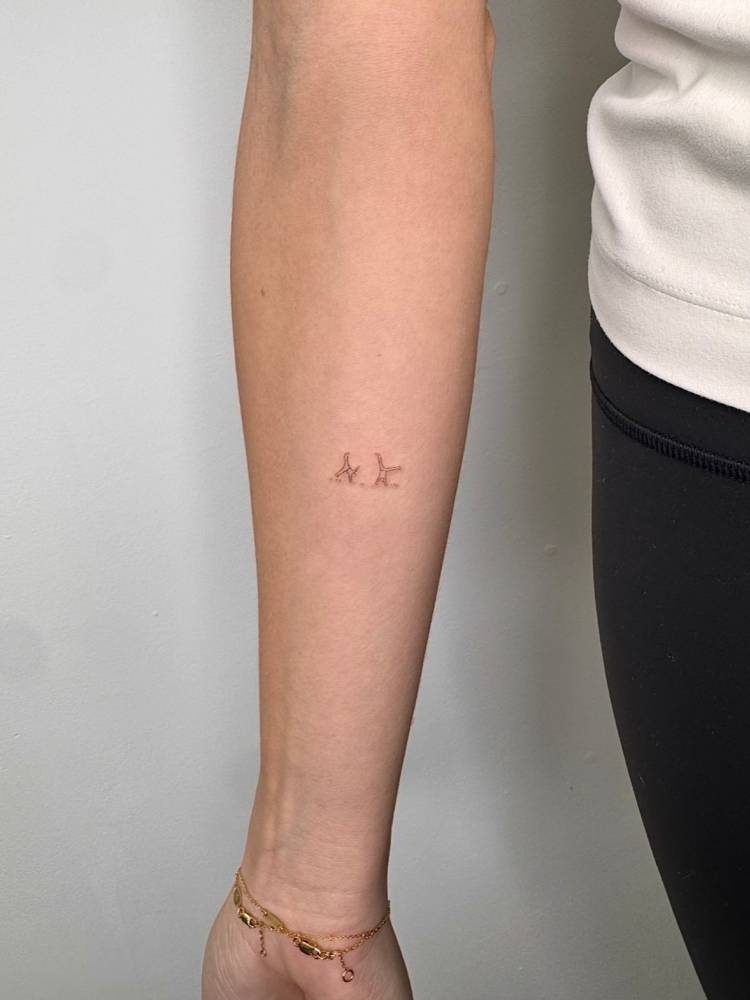 Little minimalistic gymnasts tattooed on the inner forearm.