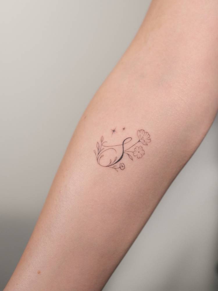 Letter "S" and flowers tattoo located on the inner forearm.