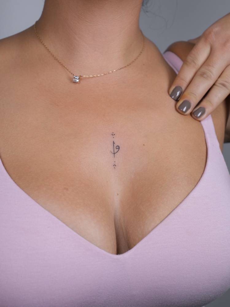Ornamental design tattooed on the sternum, minimalistic style.