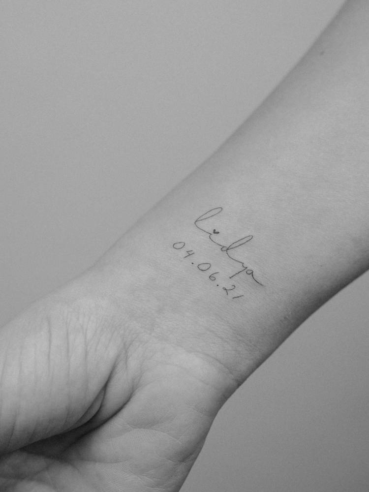 Name "Lydia" and date tattoo located on the wrist.