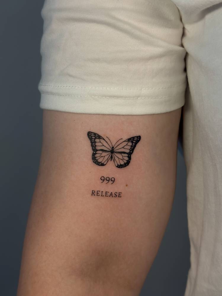Butterfly, number "999" and word "release" tattooed on the bicep.
