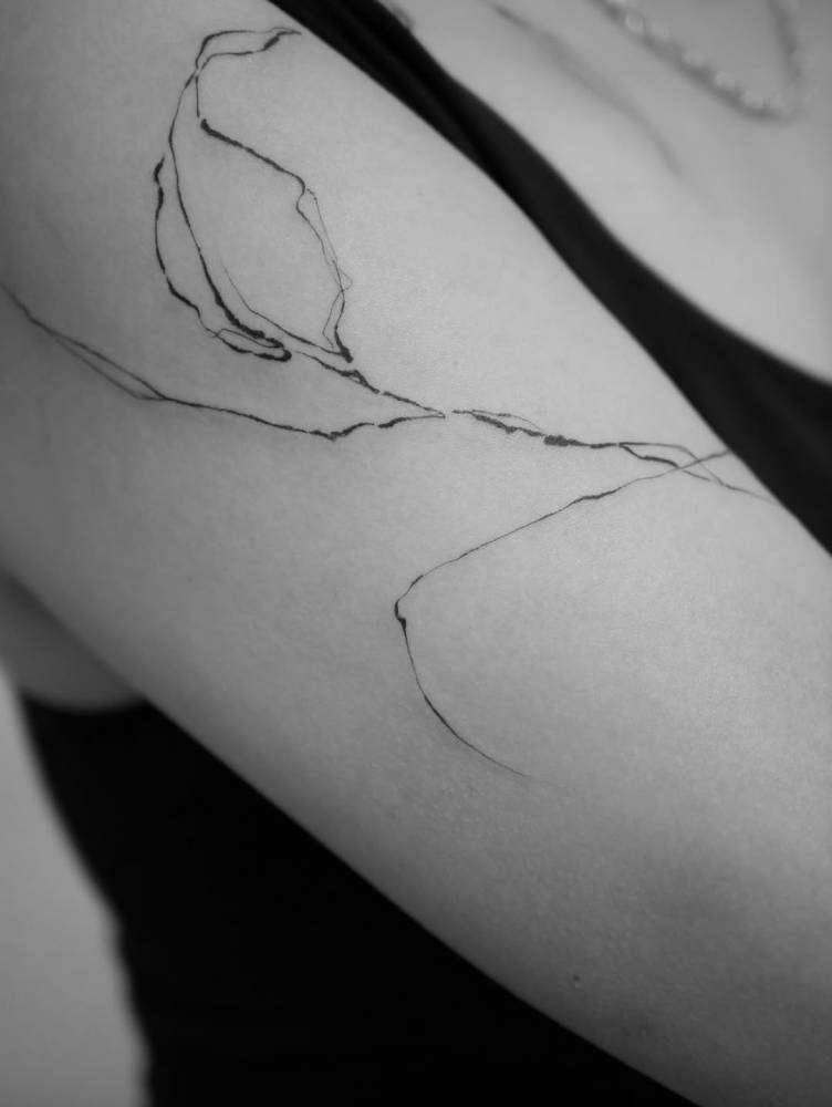 Leaf tattoo in illustrative style located on the upper arm.