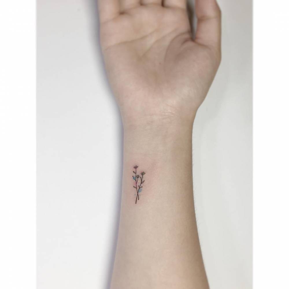 Watercolor style flowers tattooed on the wrist.