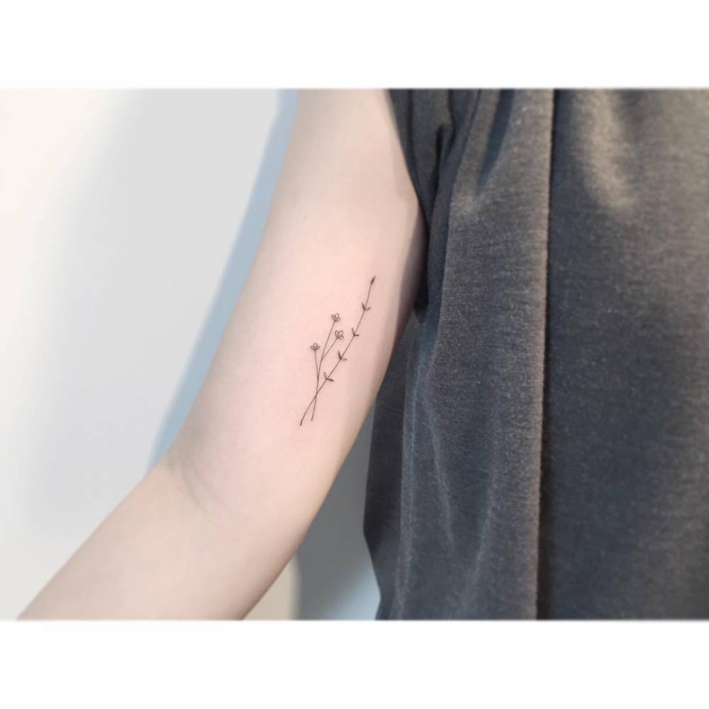 Little flowers tattooed on the inner arm, fine line style.