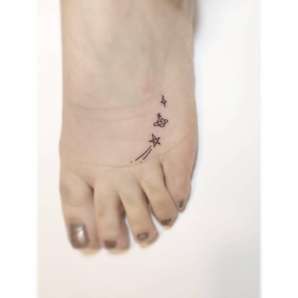 Shooting star, saturn and star tattoo located on the foot.