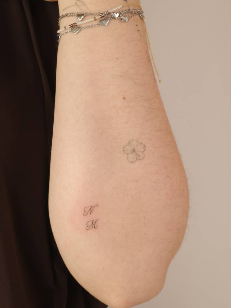 Initials "N" and "M" tattooed on the forearm.