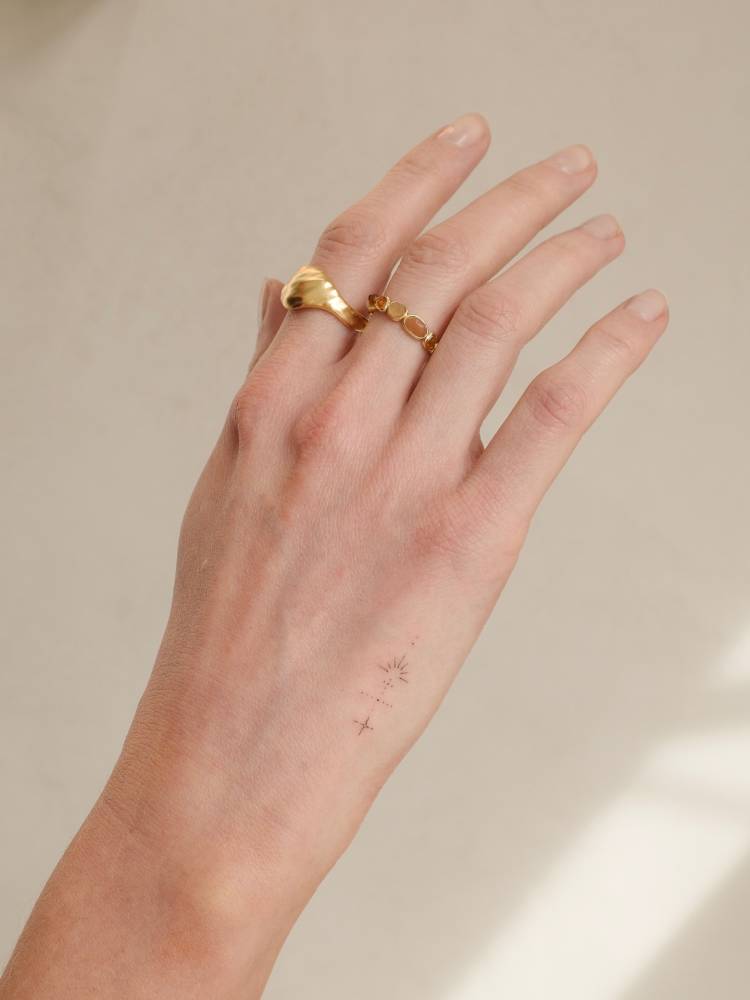 Fine line style ornamental design tattooed on the hand.