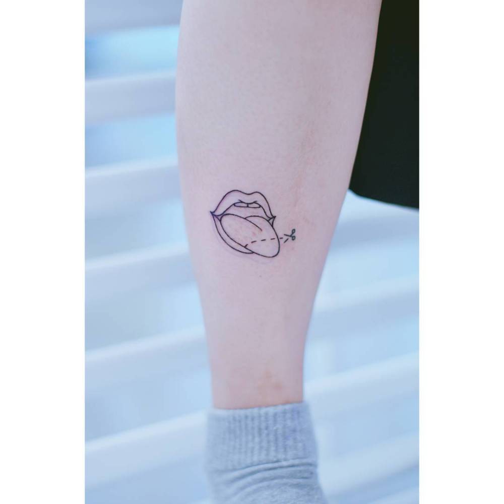 Mouth and scissor tattoo located on the shin, fine line style.