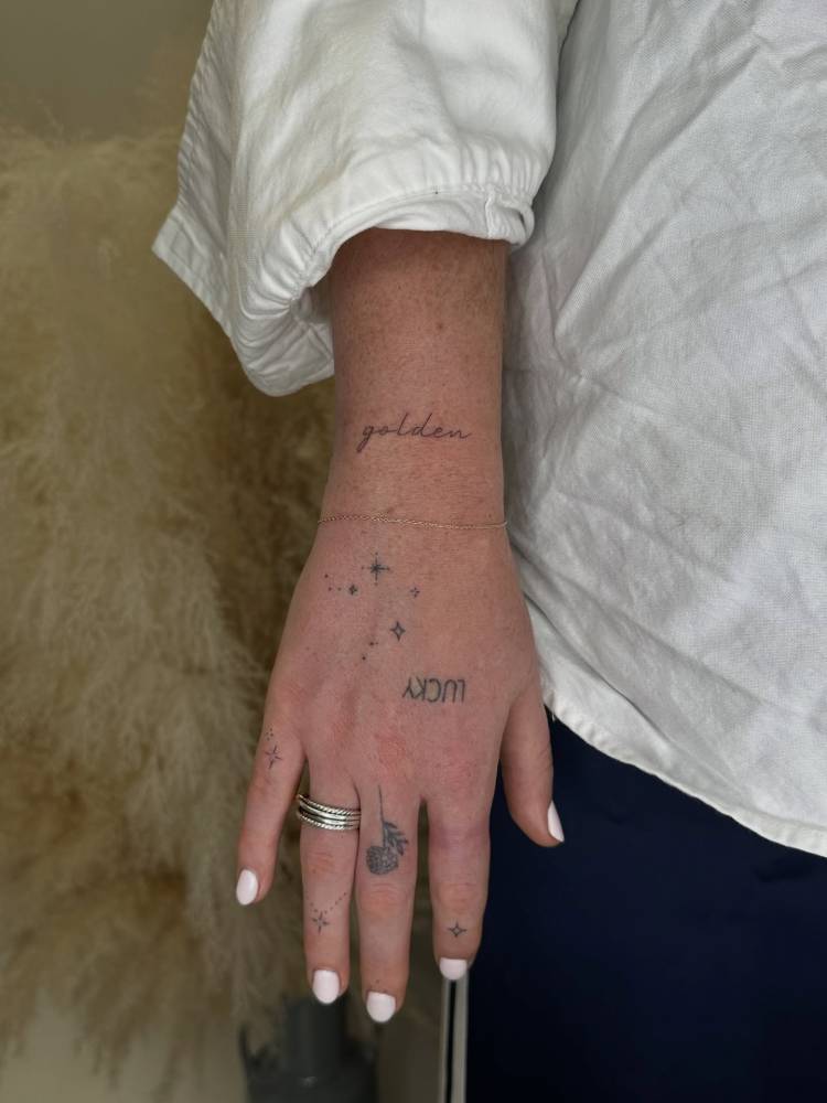 Handwritten font word "golden" tattooed on the wrist.