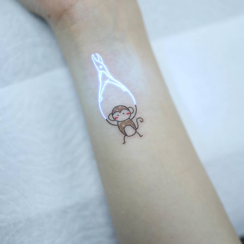 Monkey holding nail clippers tattooed on the wrist.