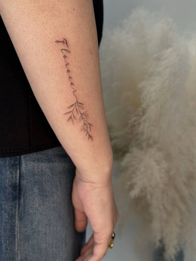 Word "florecer" and flowers tattooed on the forearm.