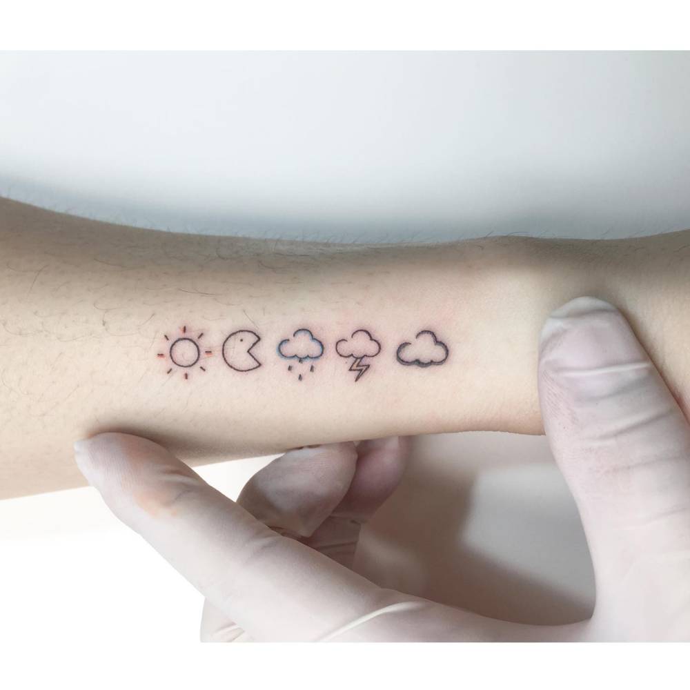 Weather symbols and Pac-Man tattoo located on the wrist, minimalistic style.