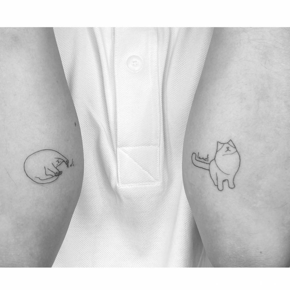 Individual matching cats tattooed on the inner arms.