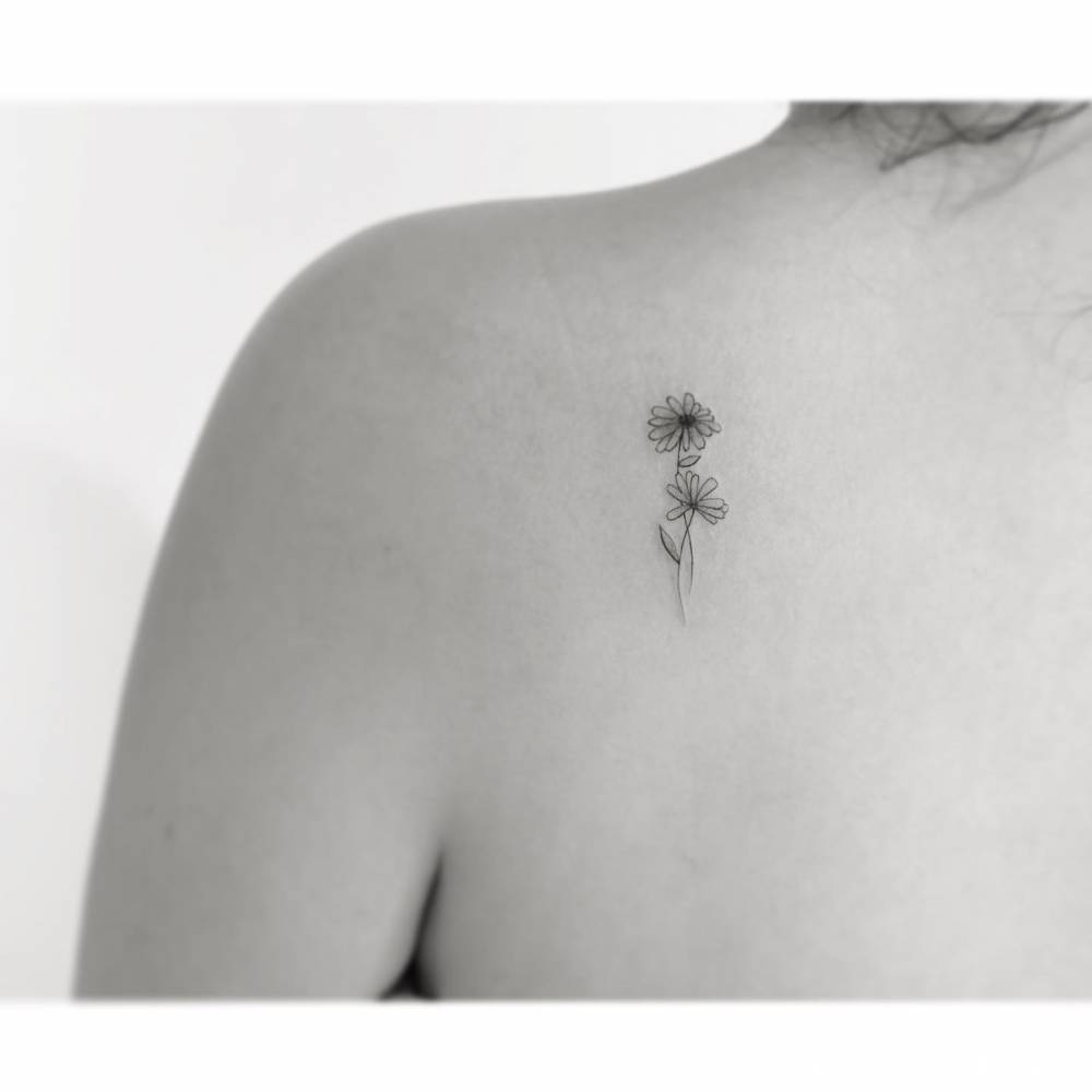 Little daisy flowers tattooed on the shoulder blade.