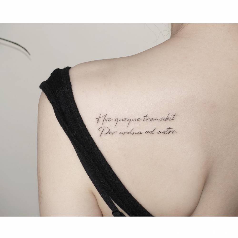 Latin quotes tattooed on the shoulder blade, handwritten font.
