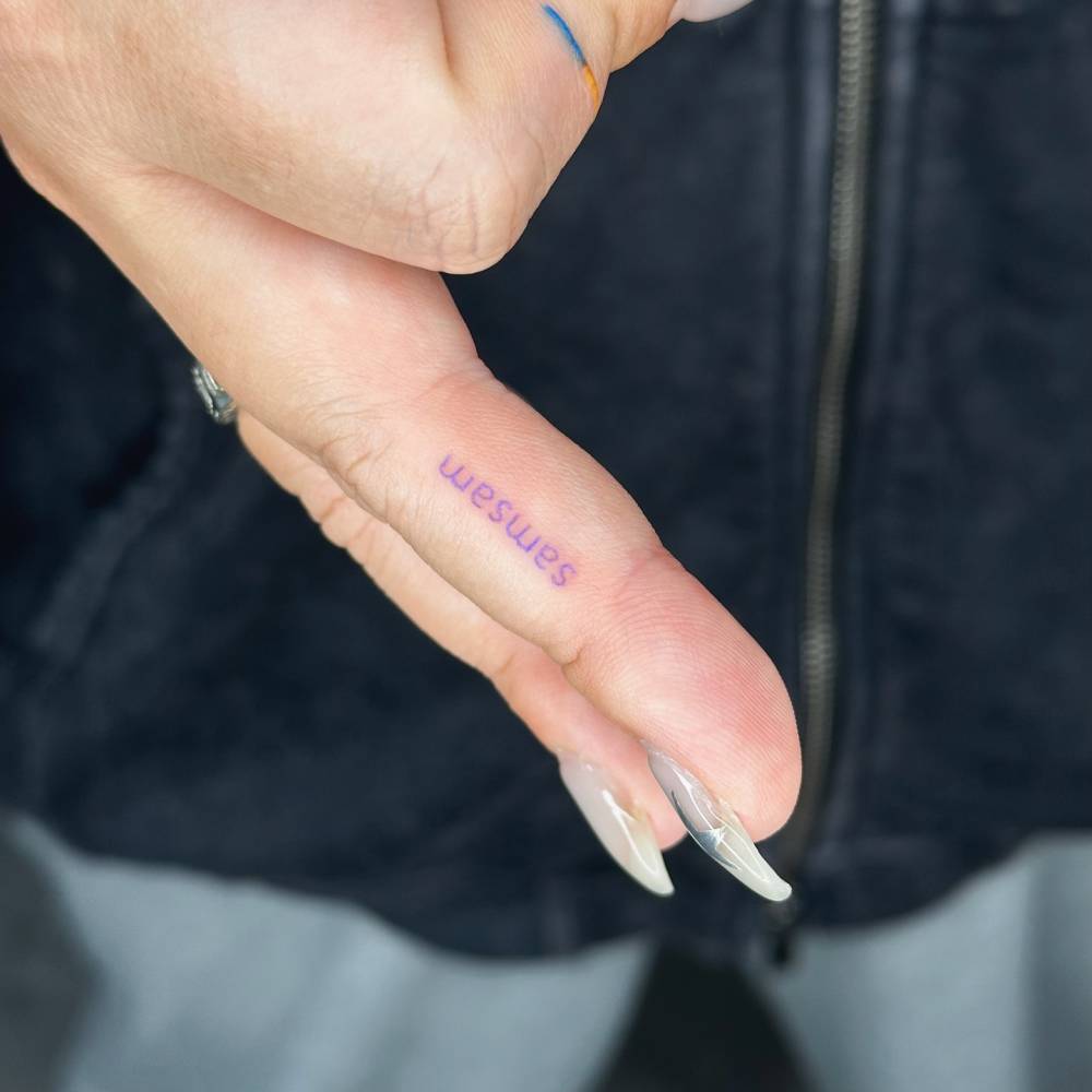 Name "Samsam" tattoo located on the finger.