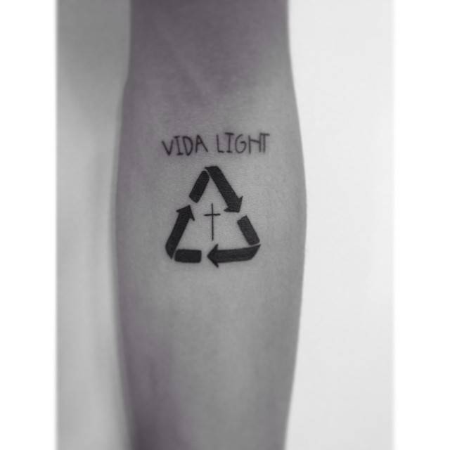 Recycling symbol and cross tattoo located on the inner forearm.
