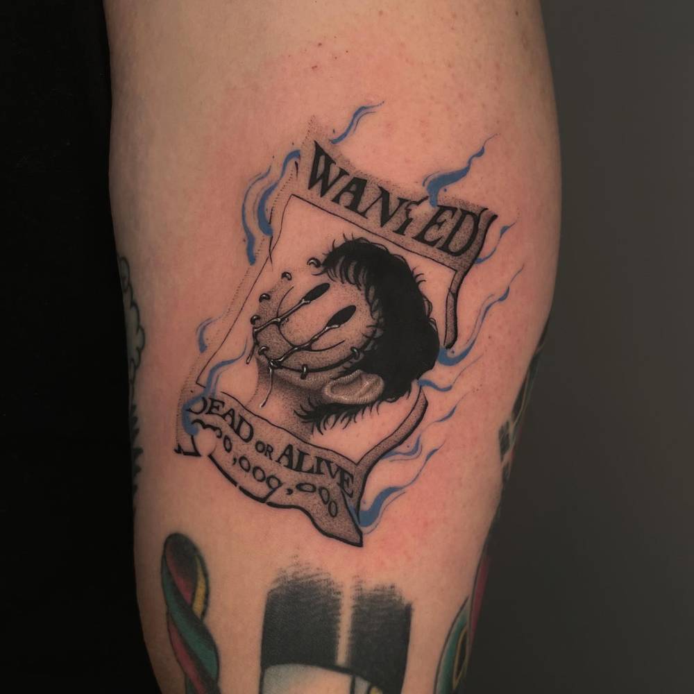 Wanted poster tattoo located on the upper arm.