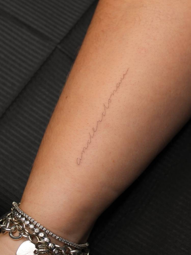 "Anderdonau" lettering tattoo in handwritten font placed on the wrist.