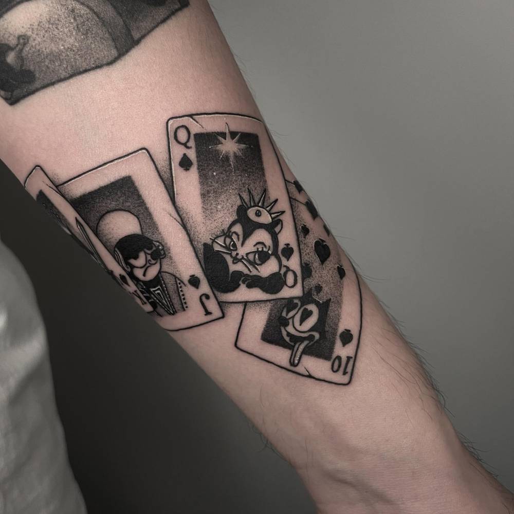 Felix The Cat playing cards tattooed on the inner forearm.