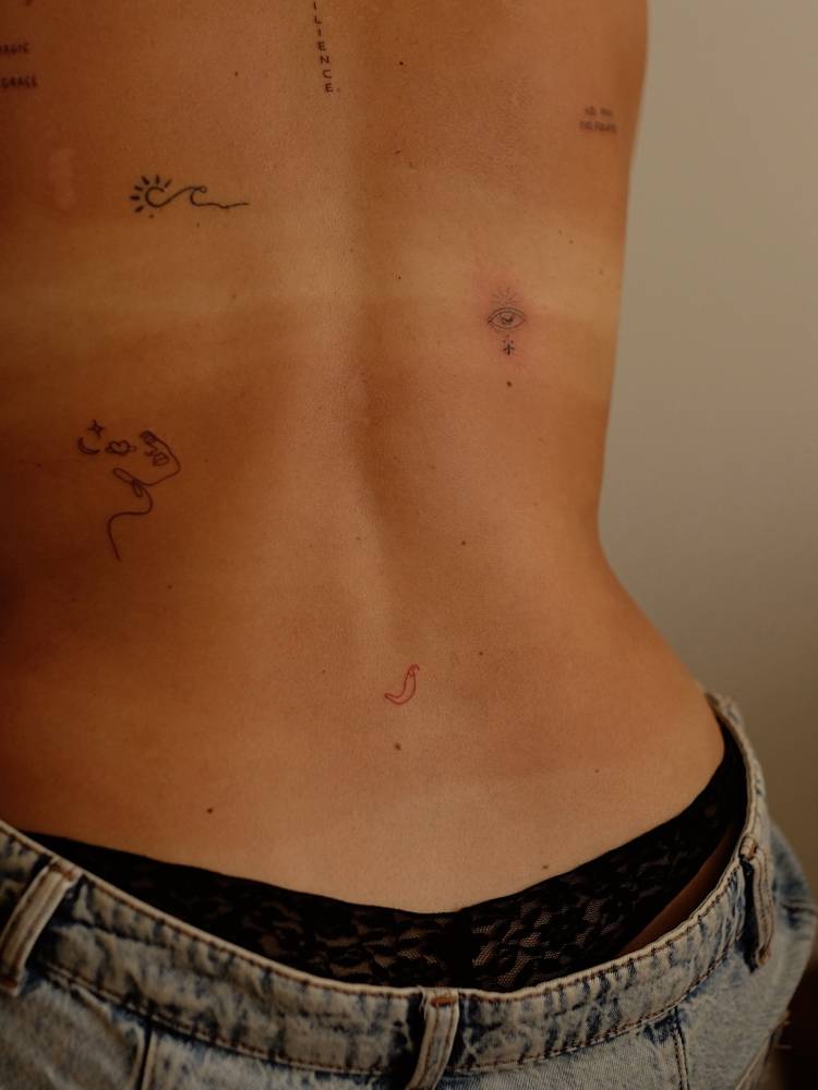 Tiny minimalistic red chili pepper tattoo located on the lower back.