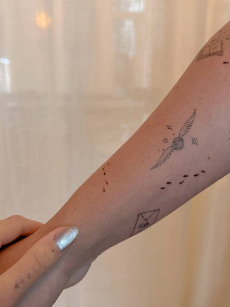 Little footprints in minimalistic style tattooed on the forearm.