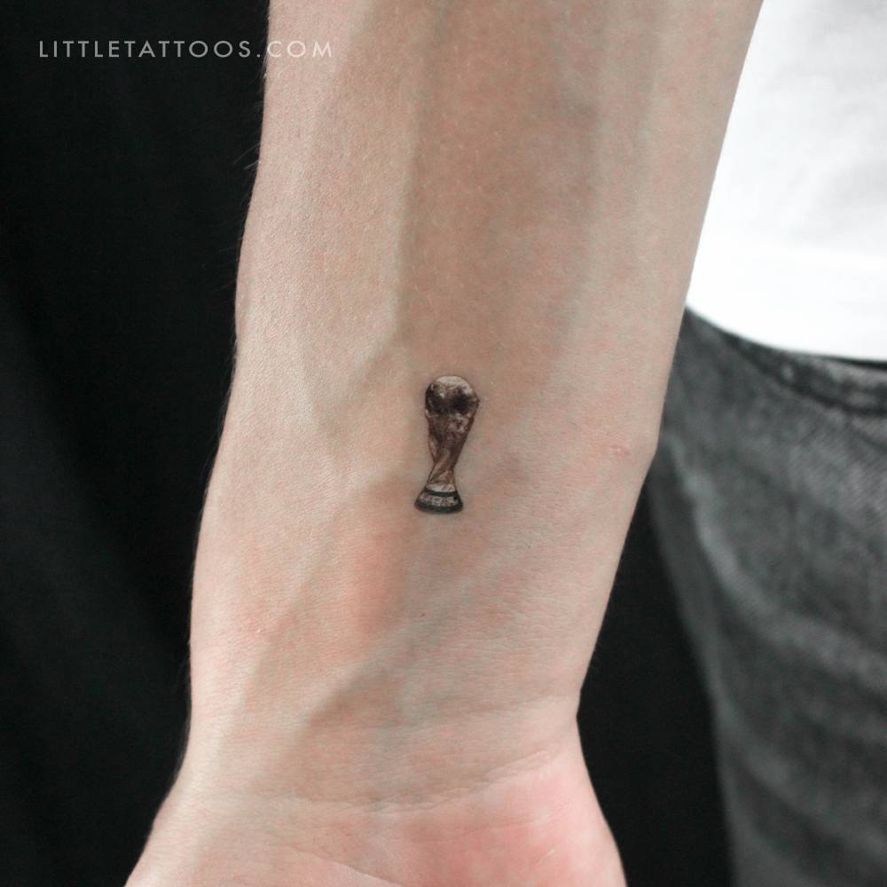 Micro-realistic style World Cup trophy temporary tattoo located on the wrist.