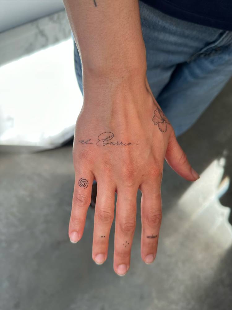 "El Barrio" and spiral tattoos located on the hand.
