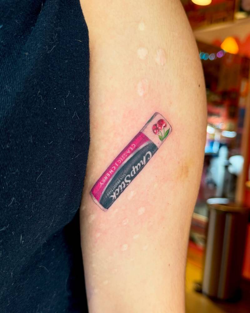 ChapStick tattoo located on the upper arm, realistic style.