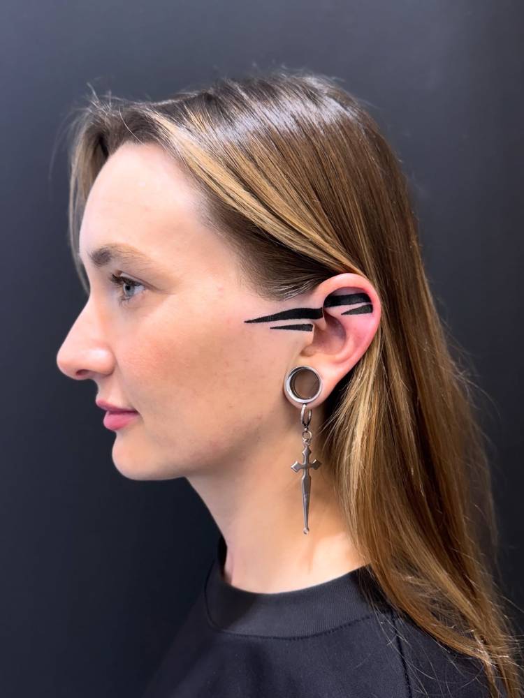 Hand poked tribal design tattooed on the face and ear.