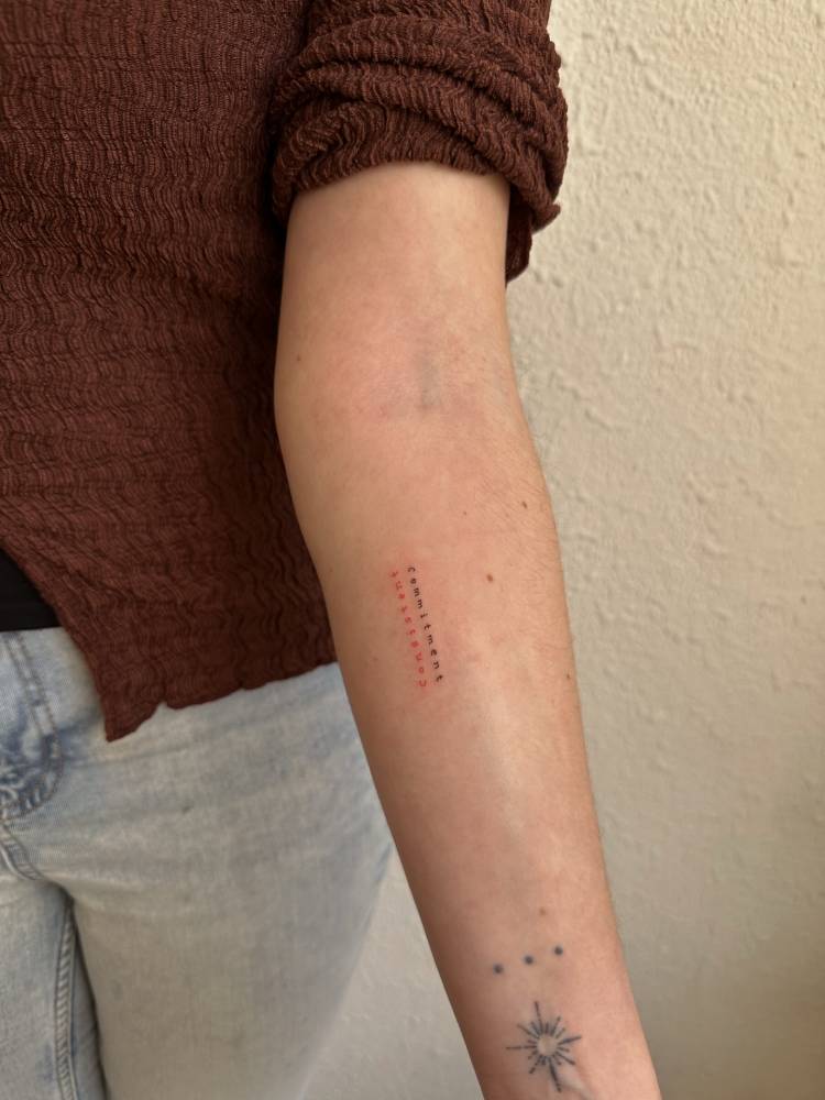 "Consistent commitment" lettering tattoo in typewriter font.