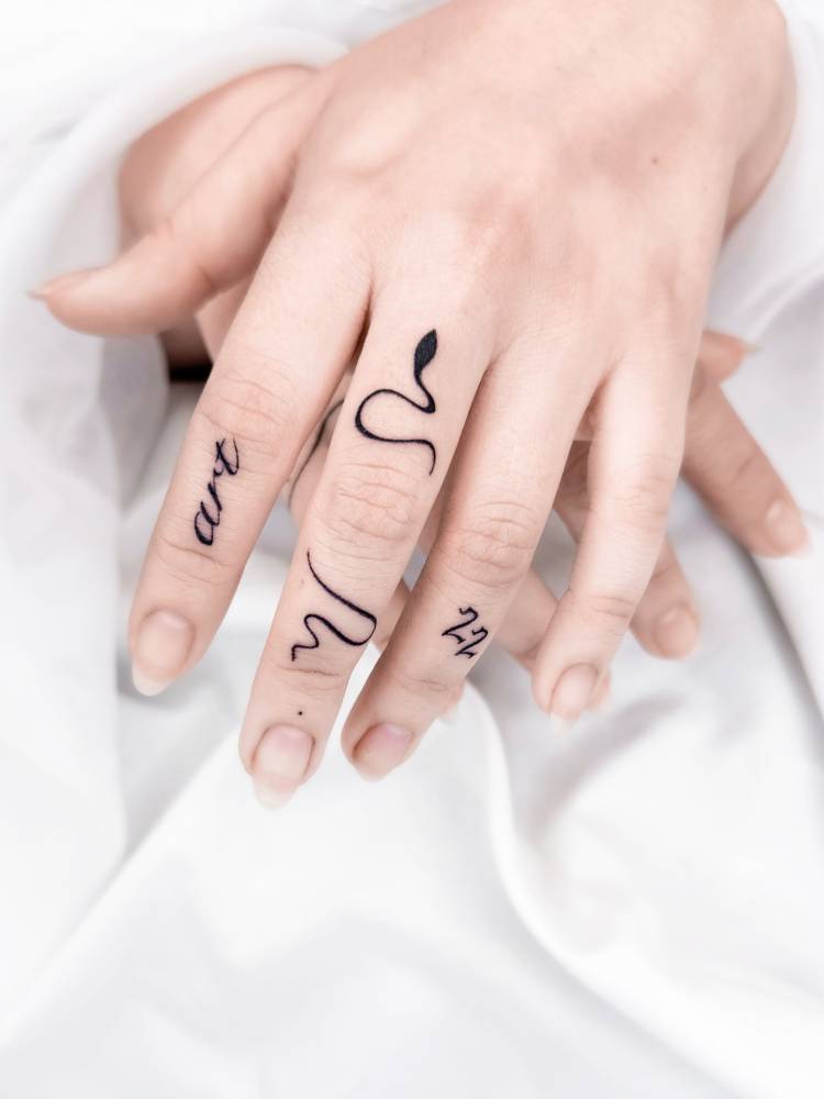 Word "art", snake and number "22" tattooed on the fingers.