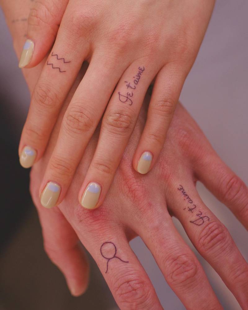 Matching "je t'aime" and zodiac symbol tattoos for couple.
